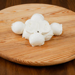 Bocconi di latte di bufala tagliato su tagliere di legno.