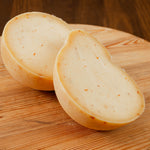 Caciocavallo al peperoncino tagliato in due su tagliere di legno.