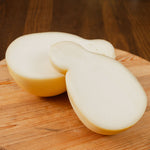 Caciocavallo semistagionato tagliato in due su tagiere di legno.