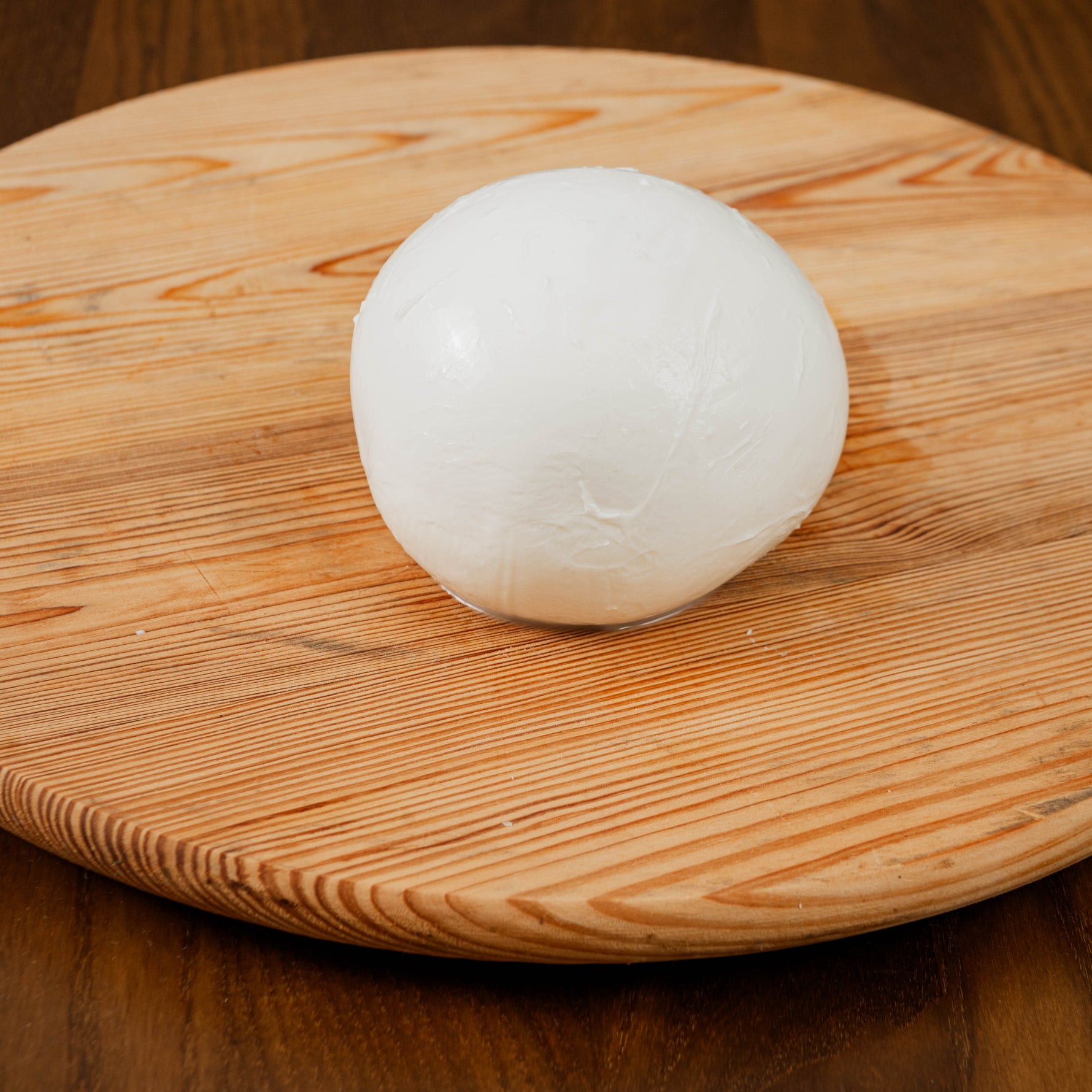 Mozzarella aversana di latte di bufala su tagliere di legno.