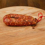 Salsiccia stagionata piccante su tagliere di legno.