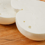 Scamorza di bufala tagliata in due su tagliere di legno.