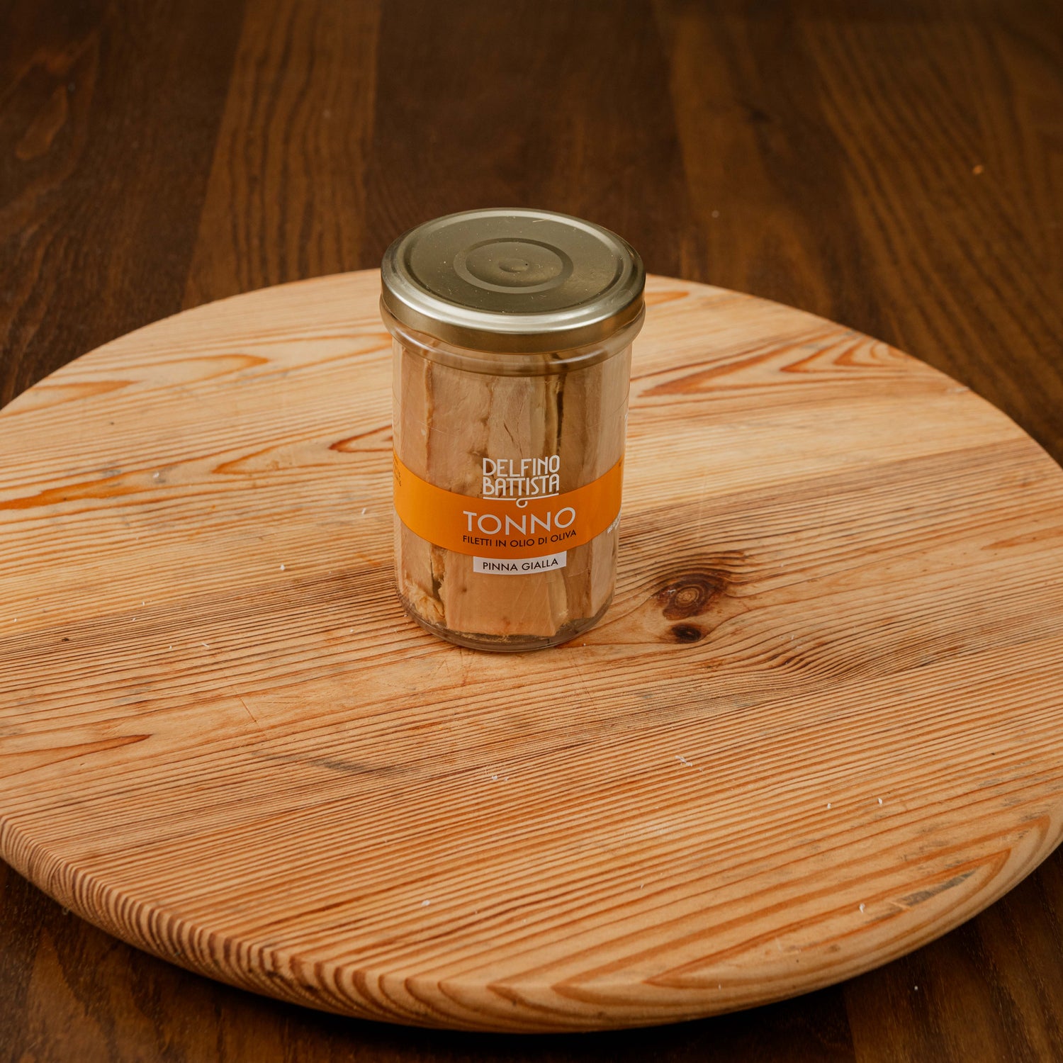 Vasetto di filetti di tonno all'olio di oliva su tagliere di legno.