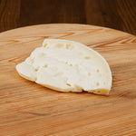 Pezzo di formaggio caciocchiato lo conte su tagliere di legno.