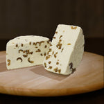 Formaggio fresco di pecora prataiola alle olive tagliato in due su tagliere di legno.