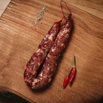 Salsiccia Piccante su tagliere di legno con peperoncino.