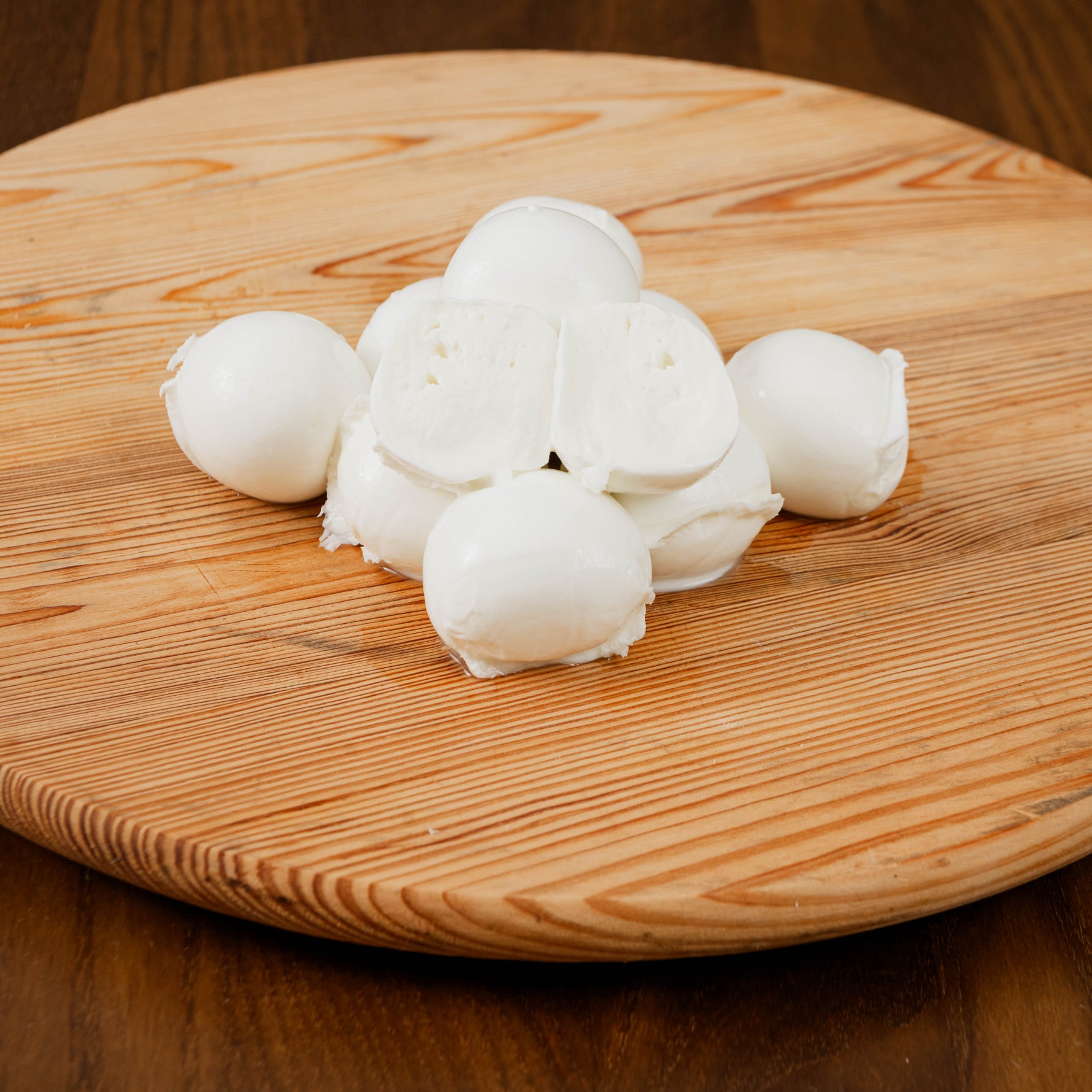 Bocconi di latte di bufala tagliato su tagliere di legno.