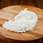 burrata di bufala tagliata con fuoriuscita di panna su un tagliere di legno.