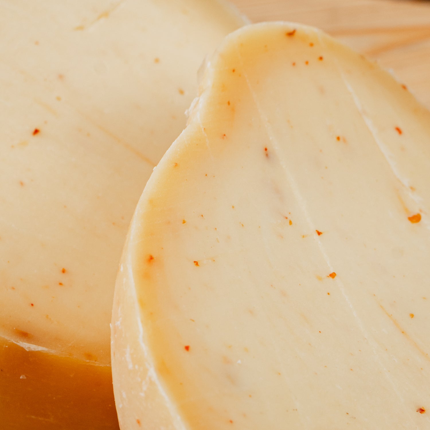 primo piano di Caciocavallo al peperoncino tagliato in due su tagliere di legno.