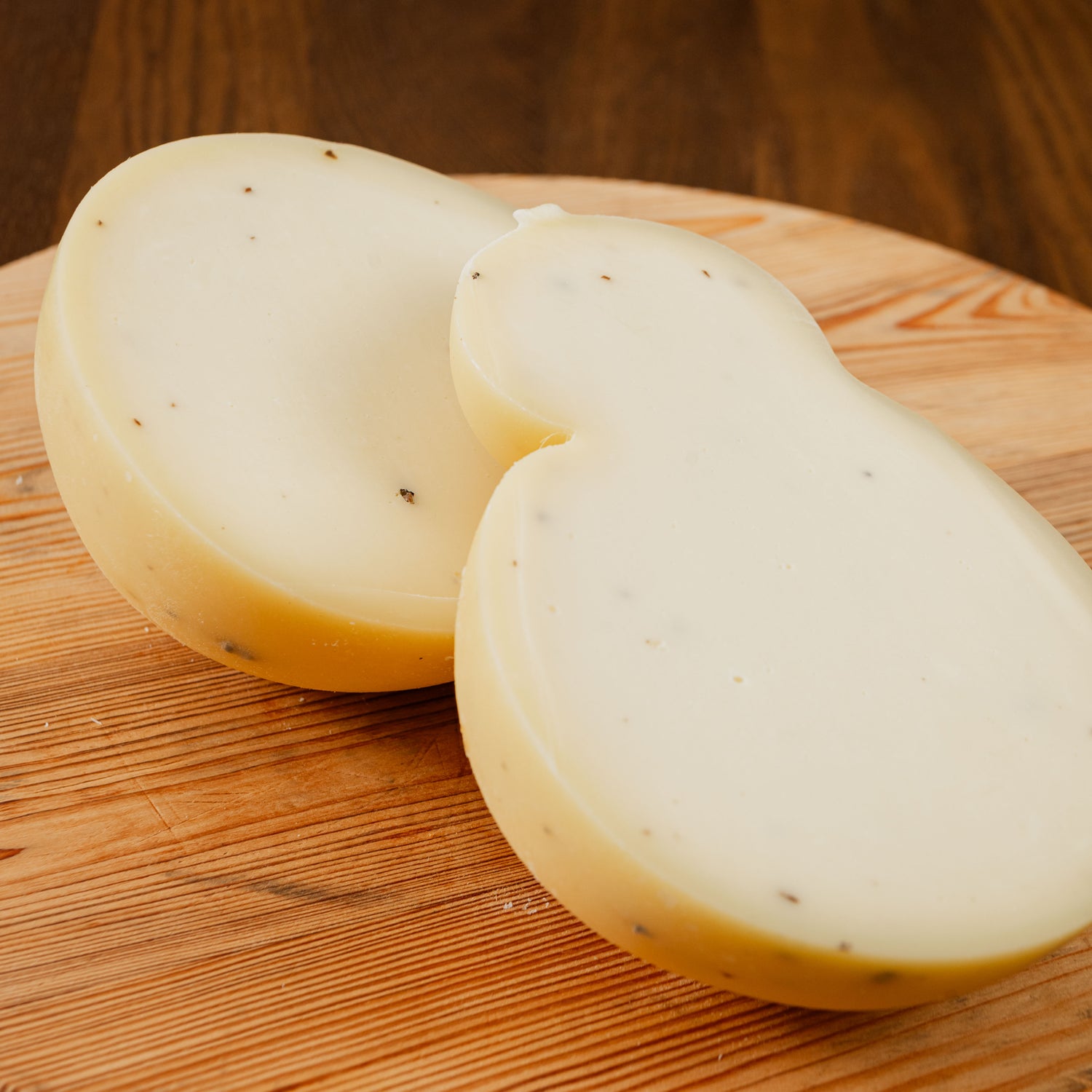 Caciocavallo al tartufo tagliato in due su tagliere di legno.