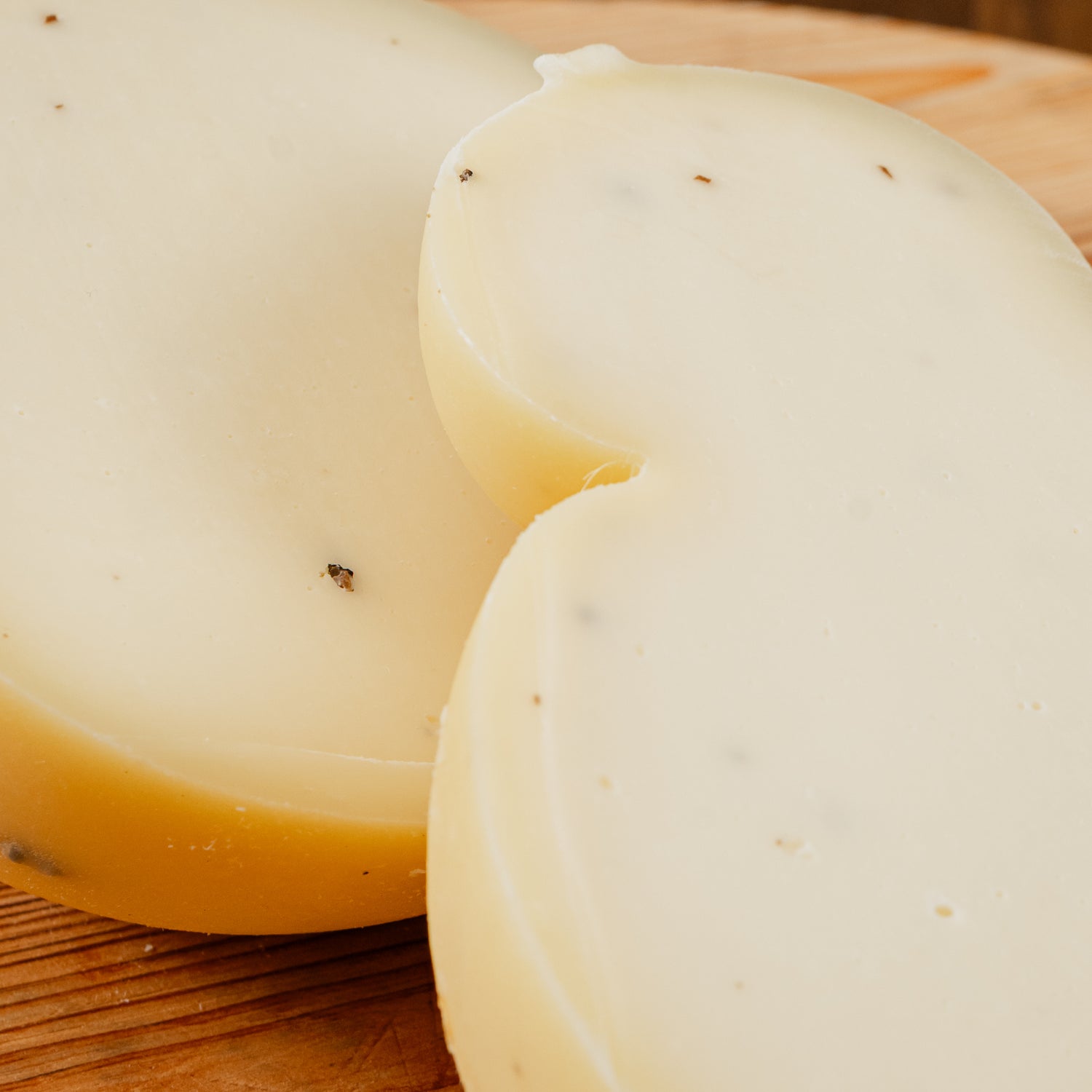 primo piano di Caciocavallo al tartufo tagliato in due su tagliere di legno.