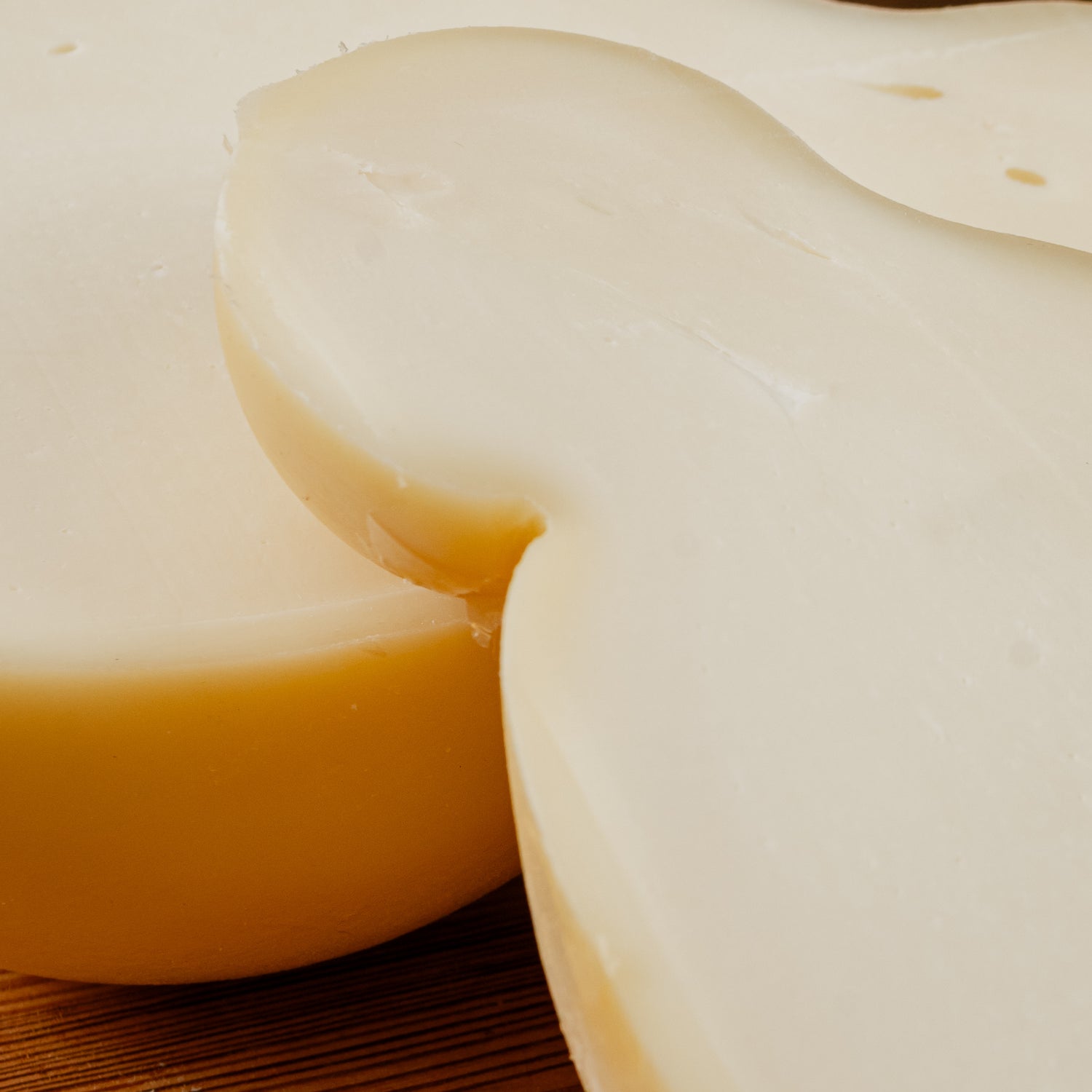 Primo piano di Caciocavallo semistagionato tagliato in due su tagliere di legno.