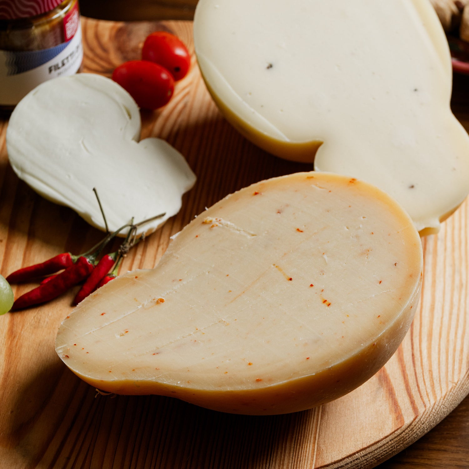 Caciocavallo al tartufo e al peperoncino  su tagliere in legno, con crosta liscia e puntini scuri visibili nella pasta.