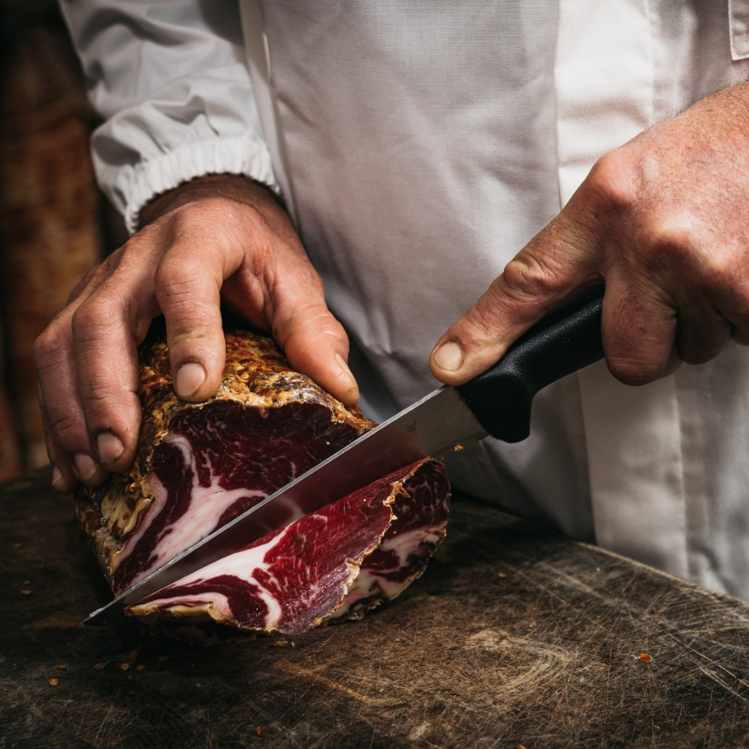 Capocollo mentre viene affettato a punta di coltello.