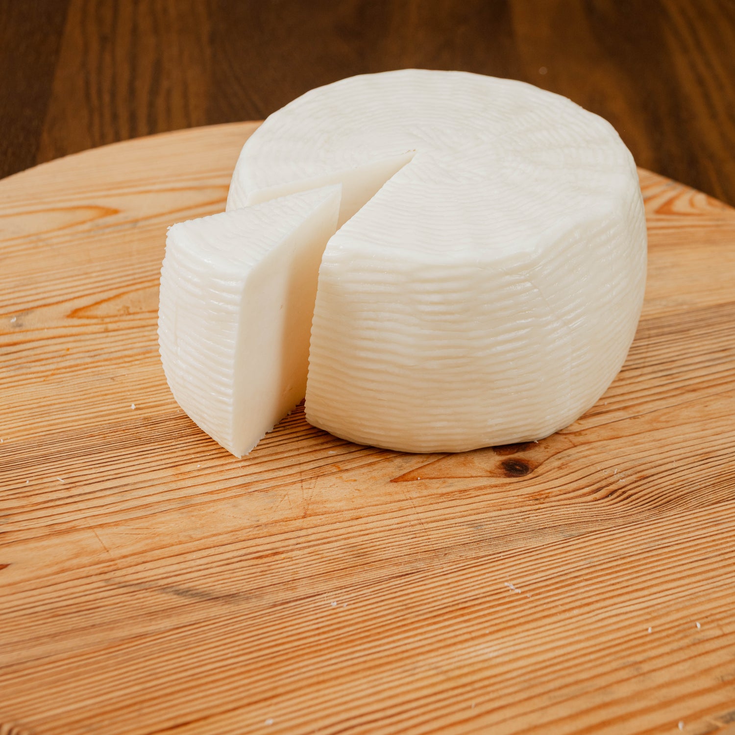 Formaggio primosale di capra tagliato a spicchi su tagliere di legno.
