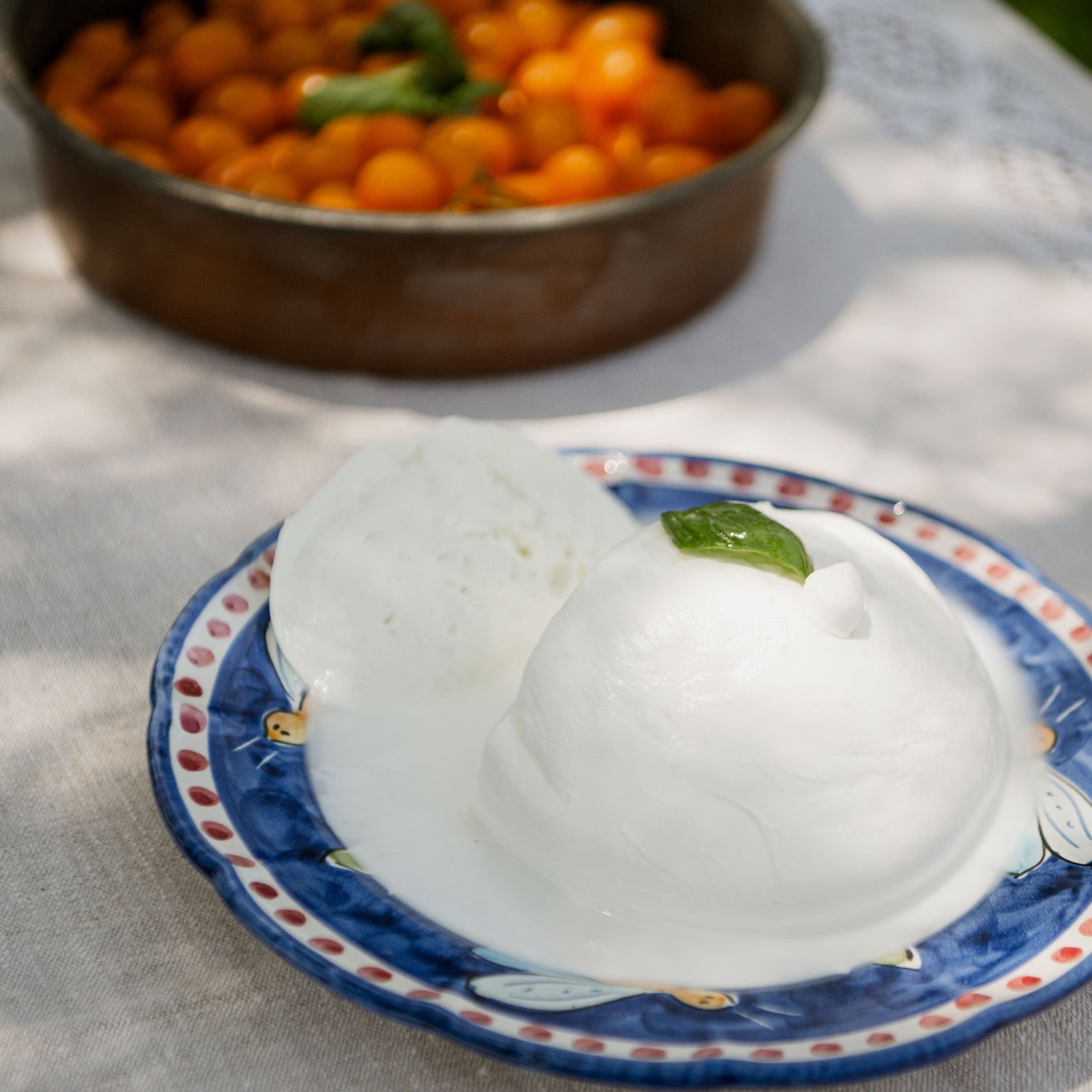 Mozzarella Gigante di latte di Bufala con datterino giallo su tovaglia di lino chiara.