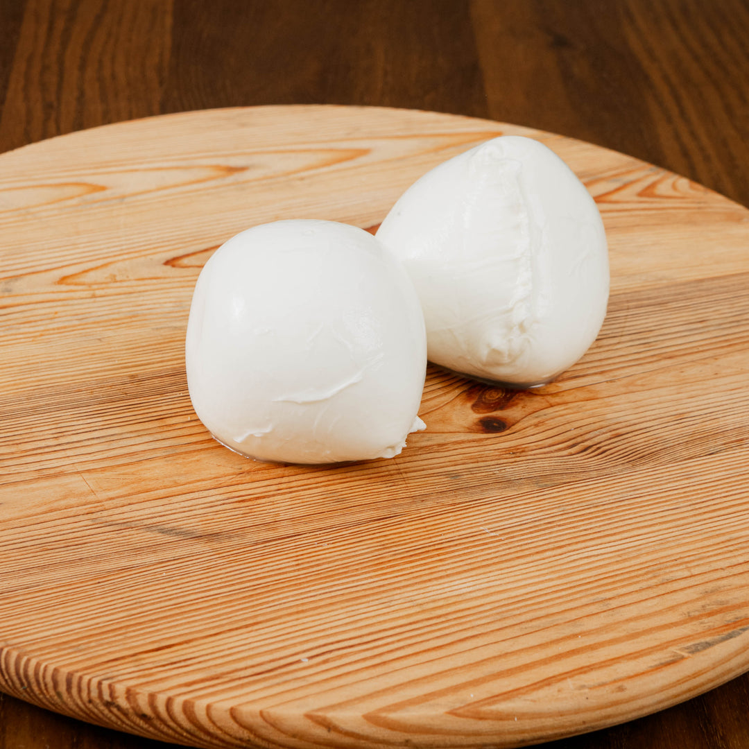 Mozzarella di latte di bufala su tagliere di legno.