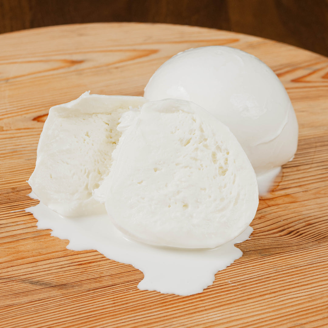 Mozzarella di latte di bufala tagliata su tagliere di legno.