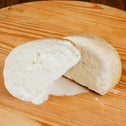 Smoked buffalo provola cut in two on a wooden cutting board.