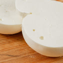 Scamorza di bufala tagliata in due su tagliere di legno.