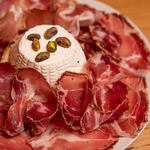 Capocollo con ricotta su tagliere di legno.
