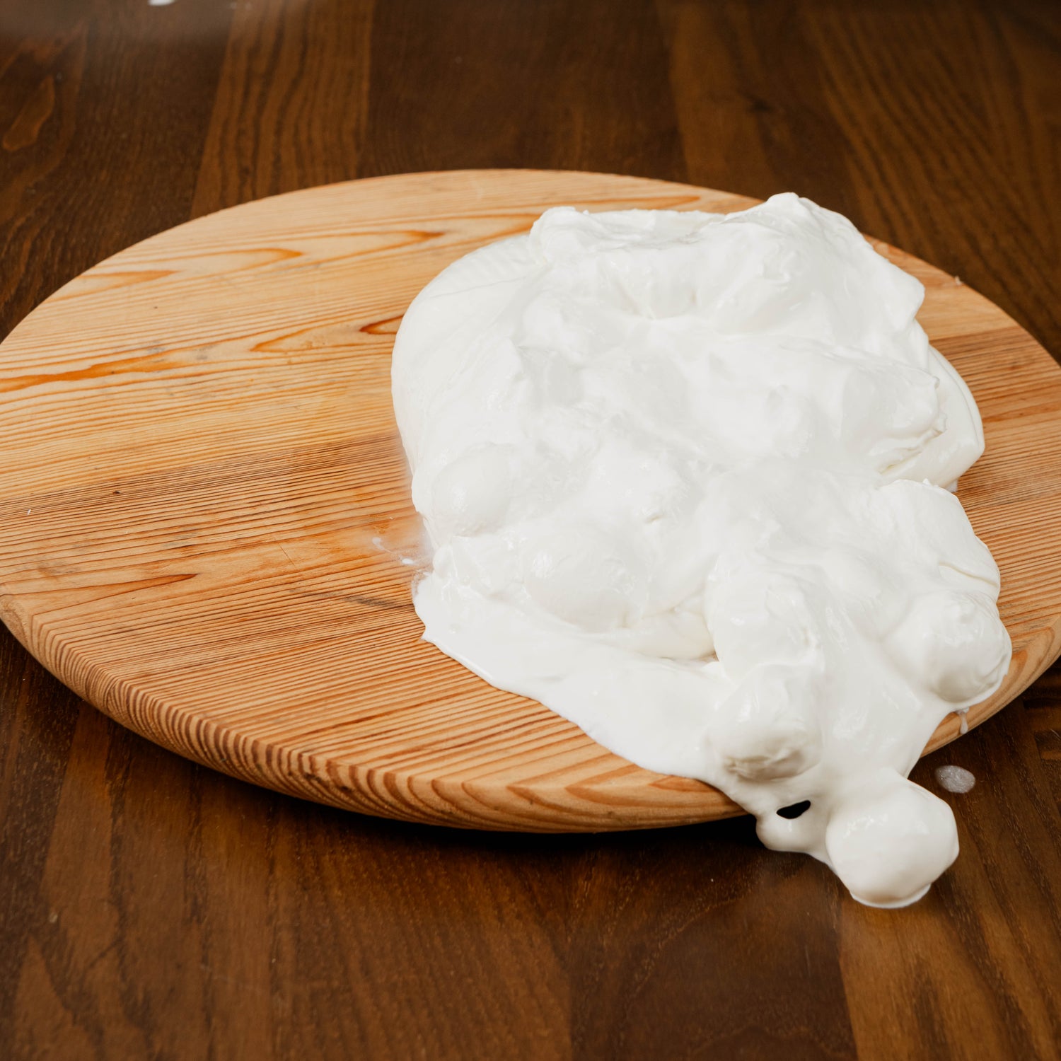 cucciolata di bufala tagliata con panna che fuoriesce su tagliere di legno.