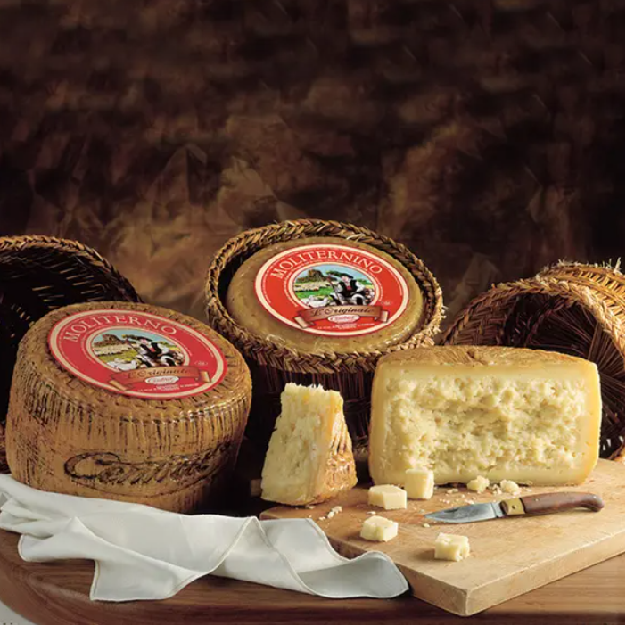 tre forme di formaggio di pecora moliterno su tavola rustica di legno.