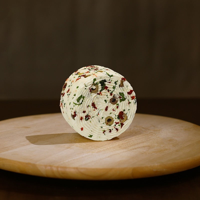Retro formaggio fresco di pecora prataiola al peperoncino, rucola e olive su tagliere di legno. 