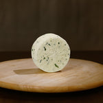Retro formaggio fresco di pecora prataiola alla rucola su tagliere di legno.