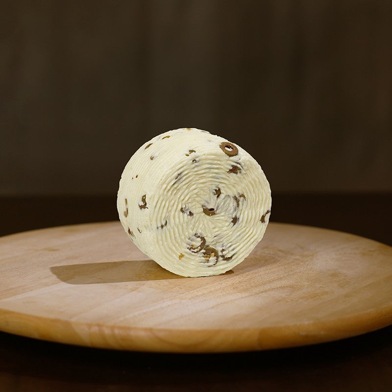 Retro formaggio fresco di pecora prataiola alle olive su tagliere di legno.