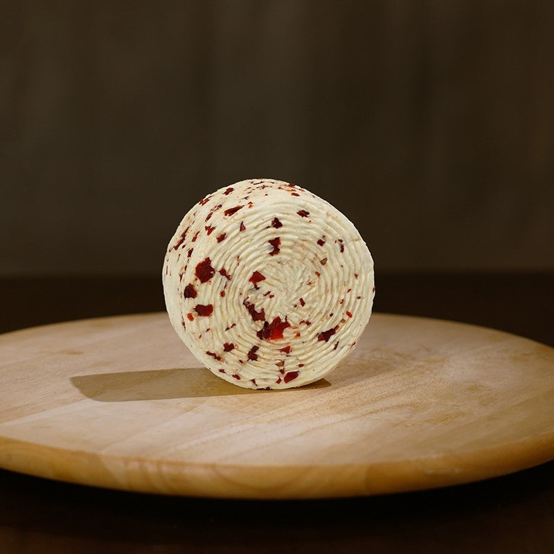 Retro Formaggio fresco di pecora prataiola al peperoncino su tagliere di legno.