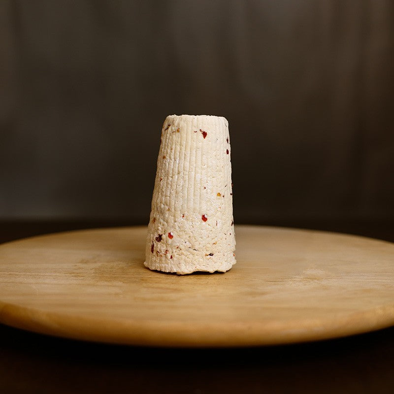 Retro di Ricotta di pecora stagionata al peperoncino su tagliere di legno.