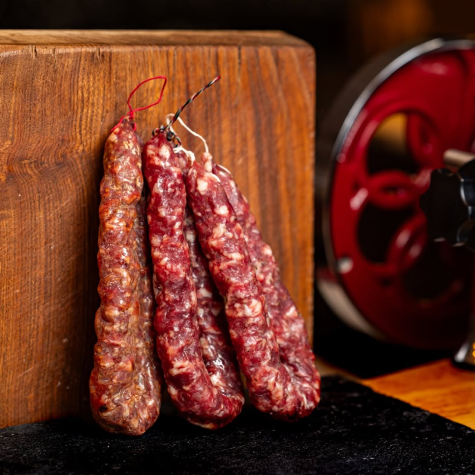 Tre Salsicce Cilentana con tagliere rustico sullo sfondo.