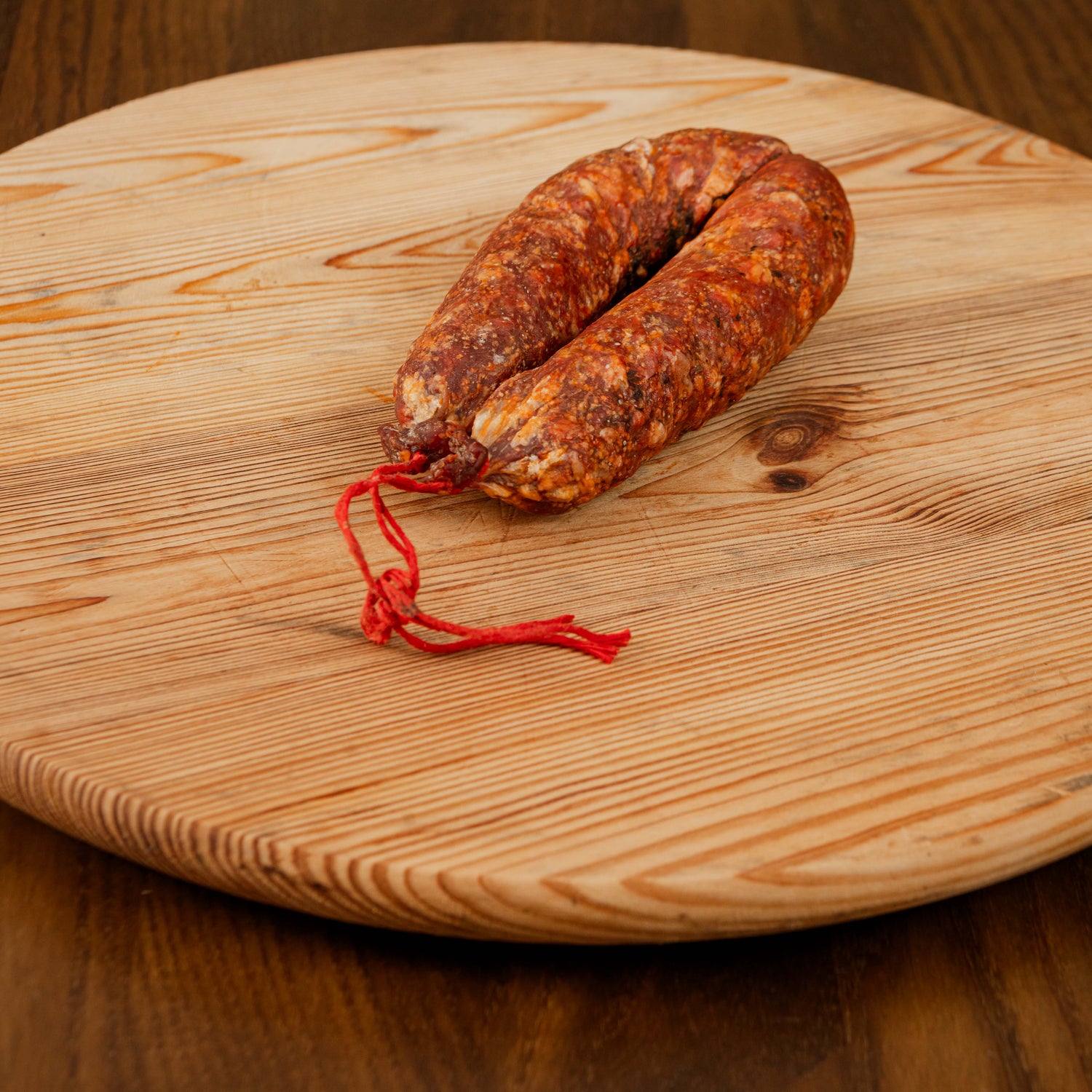 Salsiccia stagionata piccante su tagliere di legno.