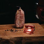 Soppressata Cilentana con Lardello intera e tagliata a fette su tagliere di legno.