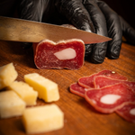 Soppressata Cilentana  con lardello su tagliere di legno tagliata a fette con formaggio.