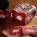 Soppressata Cilentana con Lardello tagliata a fette su tagliere di legno.